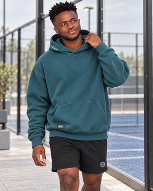 Donkere-jongen-loopt-met-Oversized-Hoodie-Kairo-op-een-padelclub